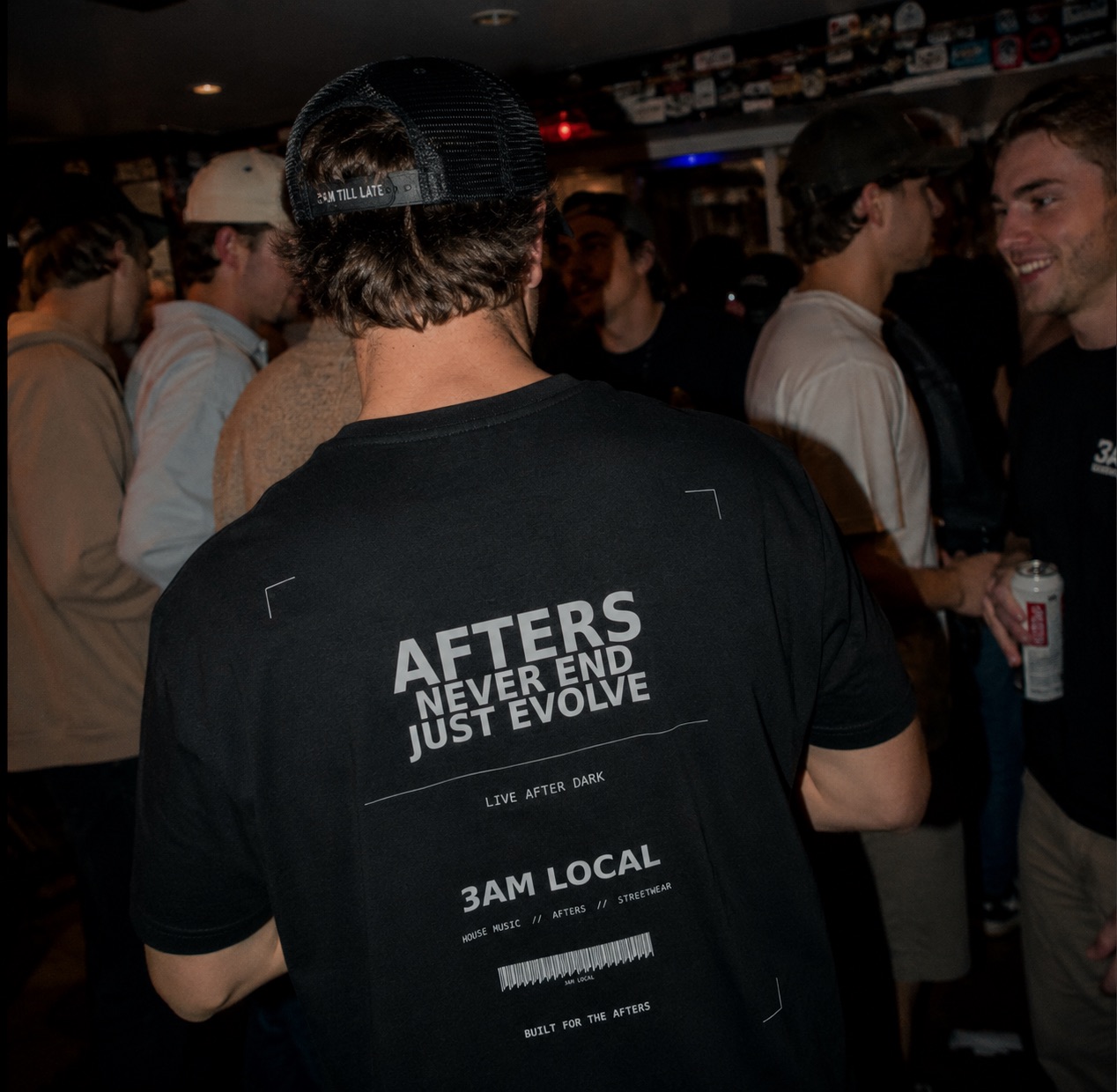 001 tee worn from behind — AFTERS NEVER END back print — at a bar