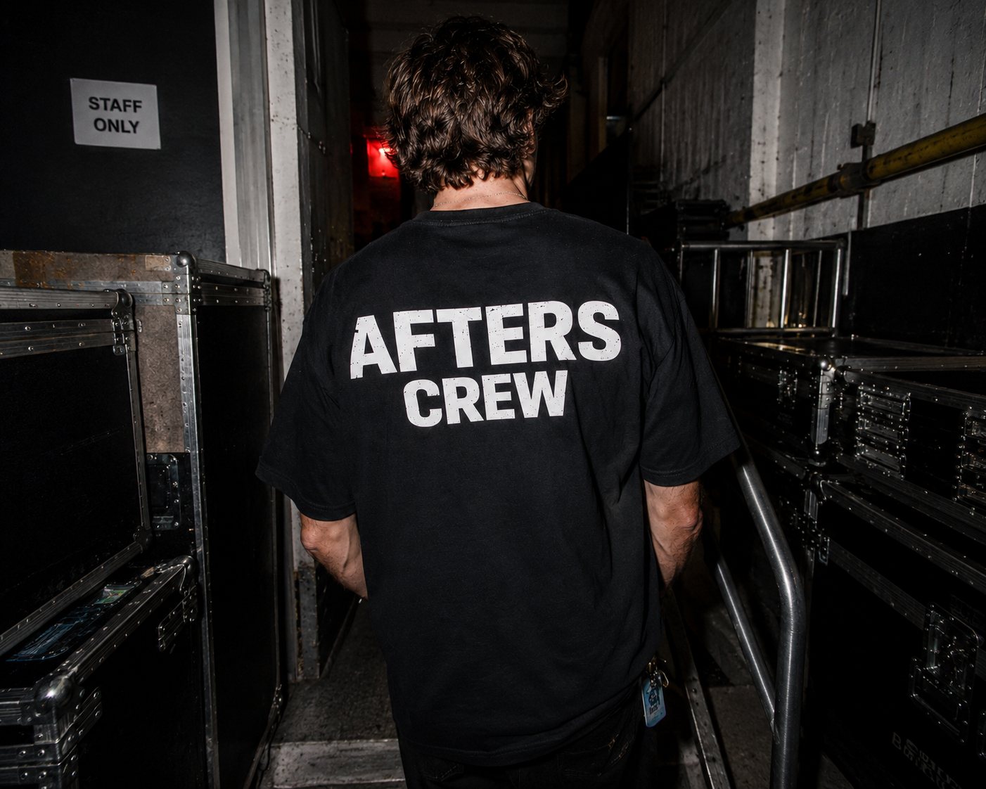 THE CREW tee worn walking a backstage staff-only corridor