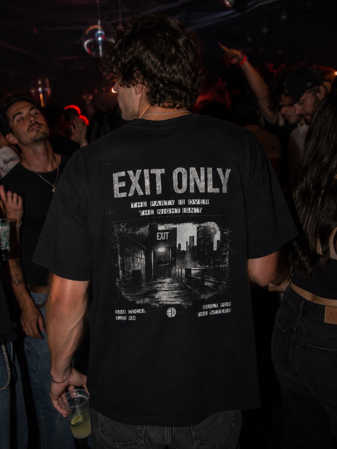 Exit Only tee worn from behind at a club under the lights