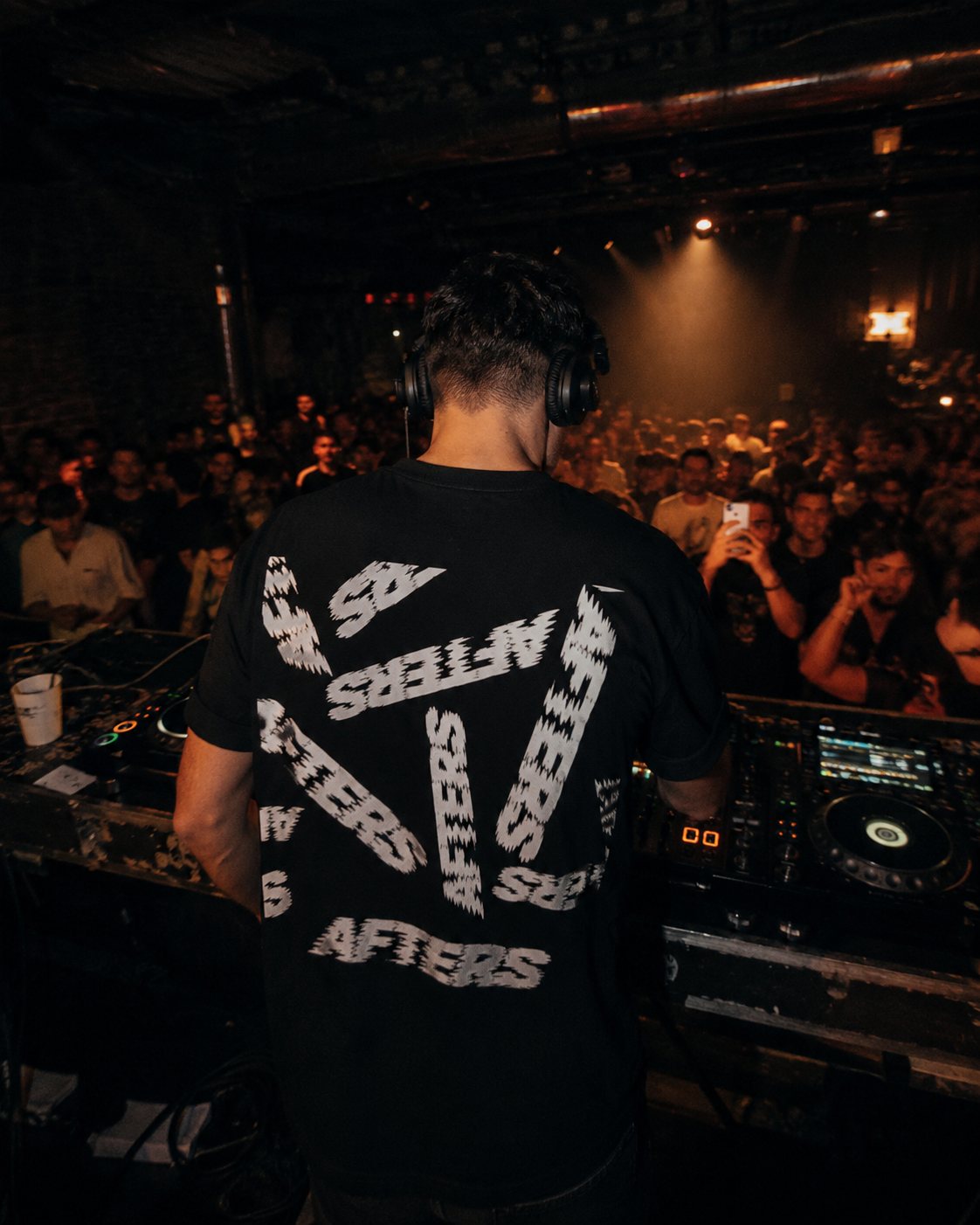 Too Far Gone tee worn by a DJ behind the decks at a warehouse party
