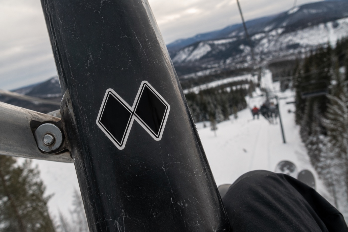 Double Black Diamond sticker on a chairlift bar with the slopes behind