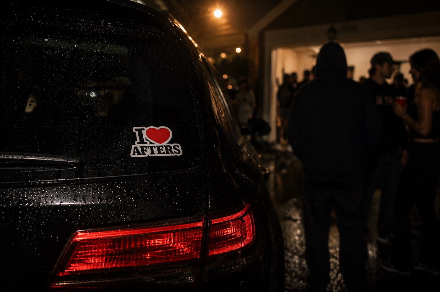 I heart Afters sticker on a rain-beaded car taillight outside a late-night party